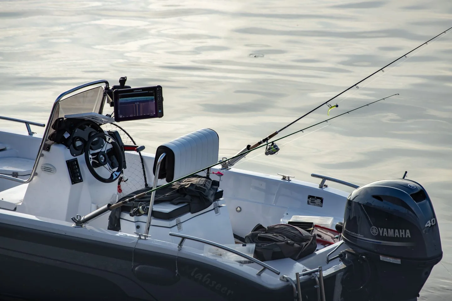 Close-up of a center-console fishing boat showing its central helm, fishing rods, and outboard motor